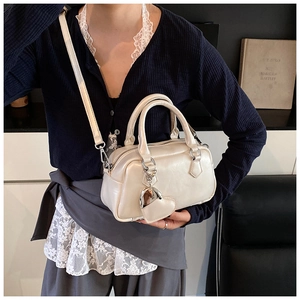 Detail of cream white leather bowling bag featuring heart mirror charm and silver zipper