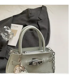 Close-up of light green lychee leather bucket bag with silver metal lock and chain strap