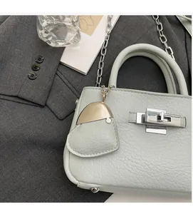 Detail of mint green lychee grain leather bucket bag with silver lock and hat charm