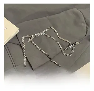 Détail de sac en cuir brillant rouge avec chaîne métallique argentée et sangle bouclée