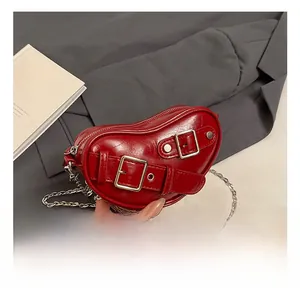 Détail du sac coeur rouge en cuir verni avec boucles argentées et bandoulière chaîne