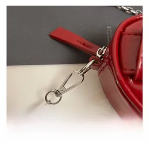 Détail du sac à main en cuir verni rouge avec chaîne en argent et tirette lisse