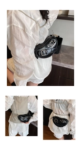 Détail d'un sac selle asymétrique en cuir verni noir avec boucles argentées et chaîne