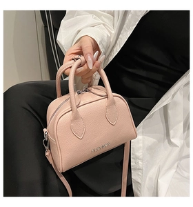 Detail of pink lychee leather texture on a compact Boston bag with silver brand plate