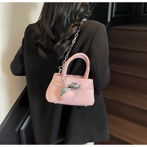 Detail view of pink mini bucket bag with silver heart charm and chain strap on model