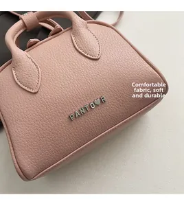 Detailed macro view of soft pink lychee grain leather and silver metal brand logo