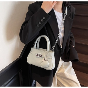 Detail of light green pebbled leather handbag with silver lock and heart charm