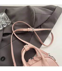 Detail of pink lychee leather handbag featuring adjustable shoulder straps and silver zippers
