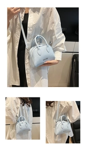 Detail of light blue Boston bag with lychee grain texture and silver metal brand logo