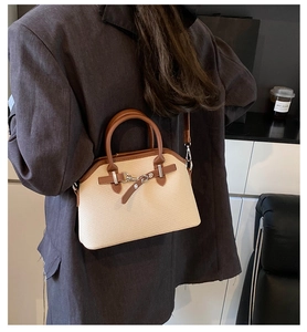 Détail du sac à main bicolore porté avec une tenue de bureau décontractée par un mannequin