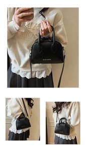 Close-up of black lychee grain Boston bag featuring dual handles and brand logo