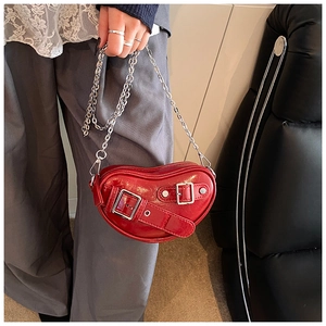 Détail du sac rouge en forme de cœur avec cuir brillant et lanière à boucle argentée