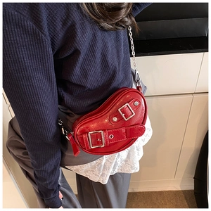 Détail d'un sac cœur en cuir verni rouge avec bandoulière chaîne et boucles argentées