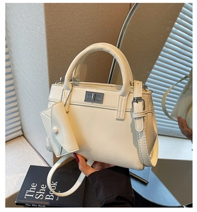 Detail of cream commute handbag featuring silver twist lock and mini pendant pouch