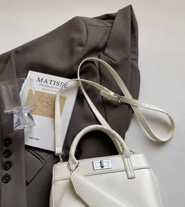 Close-up of cream leather handbag with adjustable strap and small coin purse attachment