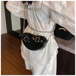 Détail du sac noir brillant avec clous punk et chaîne en argent sur le modèle