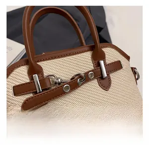 Détail de la texture tissée du sac coquillage avec garniture en cuir brun et fermoir argenté