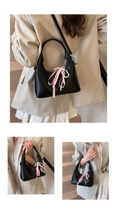 Detail of black crescent oil wax leather handbag with pearl chain and bow ribbon