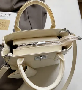 Detail view of cream white tote bag with smooth metal zipper and silver lock closure