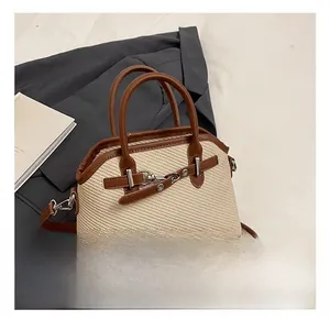 Détail d'un sac bandoulière en paille tressée avec bordures en cuir brun et fermoir