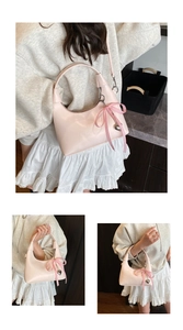 Detail view of pink hobo bag with checkered bow and heart pendant on a casual outfit