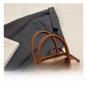 Détail des coutures contrastées, texture de paille tissée et poignée en cuir du sac