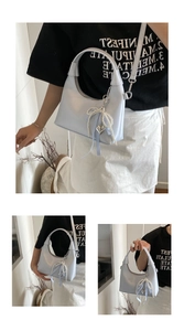 Detail of light blue hobo bag featuring pearl bow charm and checkered ribbon
