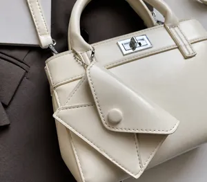 Detail of off-white tote bag with a mini envelope charm and metallic gold-tone hardware