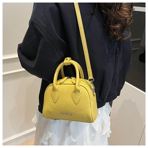 Detail of yellow litchi texture on a mini Boston bag with silver logo and dual zippers