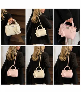 Detail of elegant crossbody bag with metal rotary lock and mini envelope charm pendant