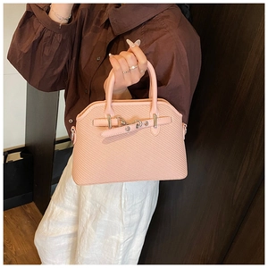 Détail du sac coquillage rose clair avec texture cuir tressé et boucle argentée
