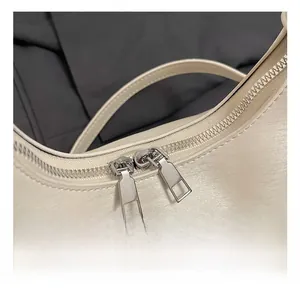 Detailed macro view of silver dual-zipper hardware on a beige leather handbag