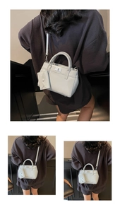 Close-up of light gray crossbody bag with silver twist lock and mini charm accessory