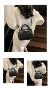 Detail of black leather handbag with metal buckle and detachable accessory pouch