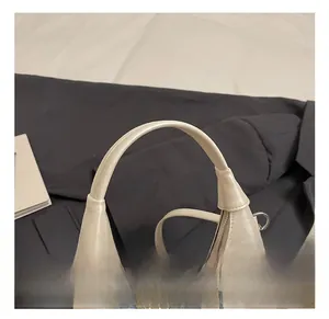 Close-up of creamy white handbag with round handle, blue bow, and pearl charm detail