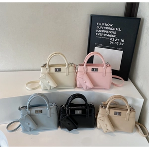 Detail view of stylish tote bags in five colors with mini envelope charms on white stands