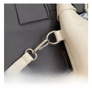 Close-up of premium silver metal hardware hook and stitched cream leather strap detail