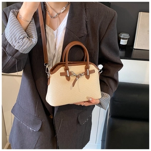 Détail du sac tissé avec bordure en cuir et boucle mors sur un blazer gris