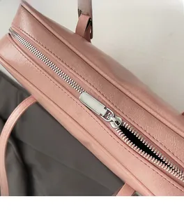 Detailopname van gladde zilveren rits en roze kunstleer met litchi-textuur op de tas