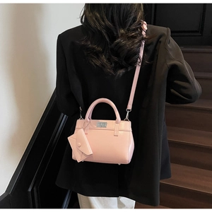 Detail of pink glossy handbag with silver metal twist lock and decorative charm