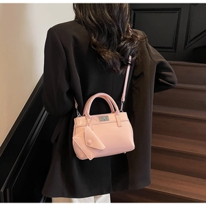 Detail of pink crossbody bag with metal twist lock and detachable mini coin pouch pendant