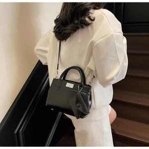 Glossy black handbag with silver buckle and triangular pouch shown on stairs