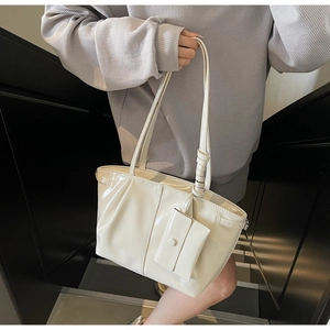 Détail d'un sac cabas crème avec texture plissée et mini pochette assortie accrochée