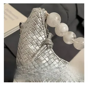 Détail de la texture tissée argentée avec une grande poignée élégante en perles blanches