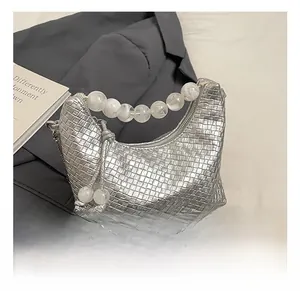 Détail du sac tissé argenté avec poignée en perles mates et bandoulière en chaîne fine