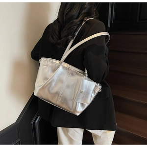 Detail der metallischen silbernen Shopper-Tasche mit Lederfalten und kleiner Tasche