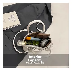 Detail showing the internal capacity of the white leather shell bag with daily essentials