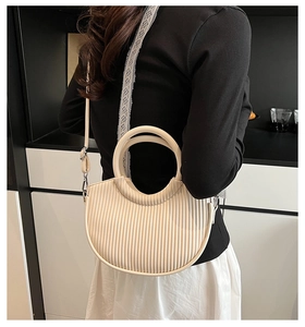 Detail view of cream pleated crescent bag with circular handle and detachable strap