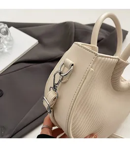 Detail view of cream pleated leather texture and bright silver metal hardware on handbag