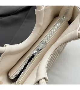 Detailed macro view of smooth metal zipper closure on the cream white leather tote bag